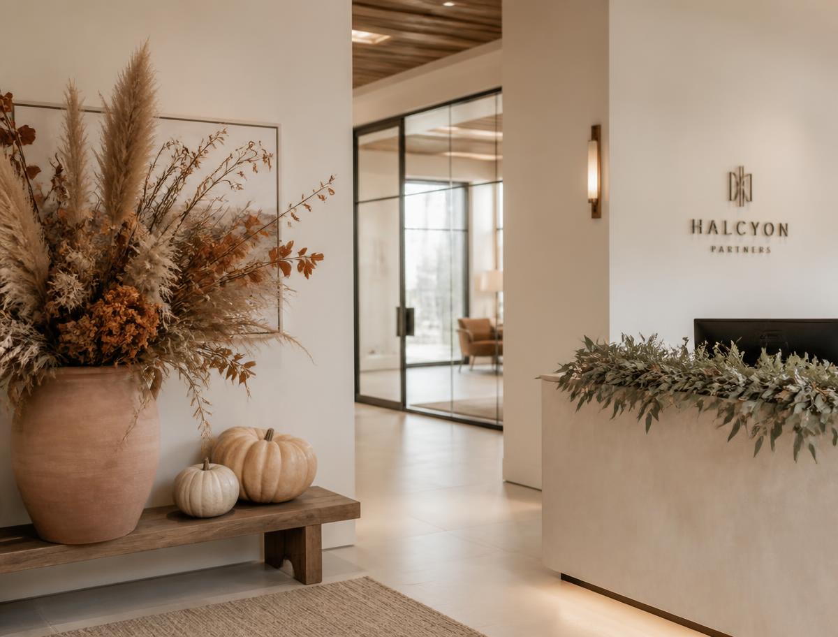 Office lobby styled with a terracotta planter of dried autumn florals, pale heirloom pumpkins on a wooden bench and sage garland on the reception desk